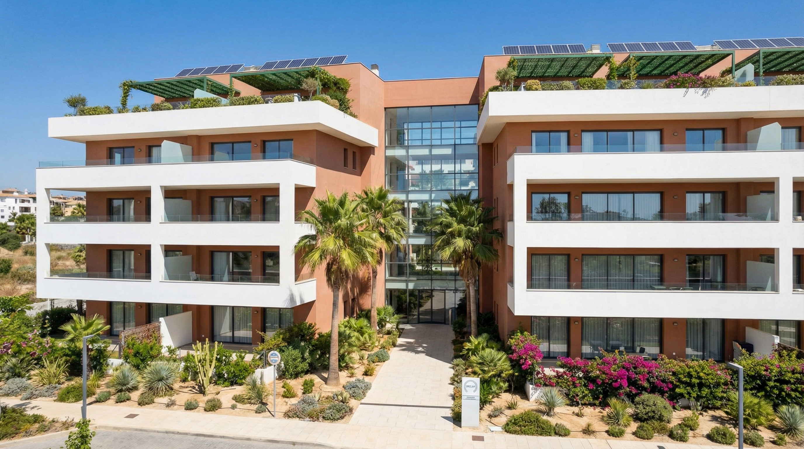 Modern residential building on the Costa del Sol showcasing energy-efficient design, large windows, and sustainable materials amidst palm trees.
