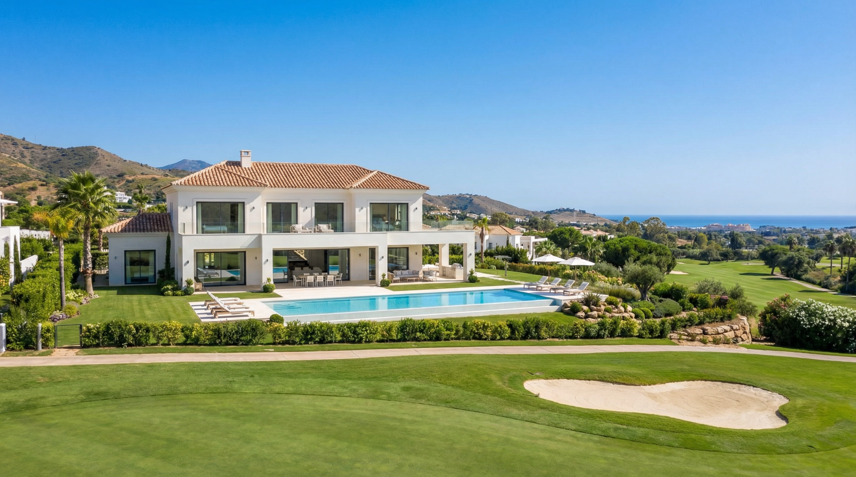 Eine moderne mediterrane Villa an der Costa del Sol mit eleganter Architektur, üppigen Gärten und einer ruhigen Außenterrasse unter einem strahlend blauen Himmel.