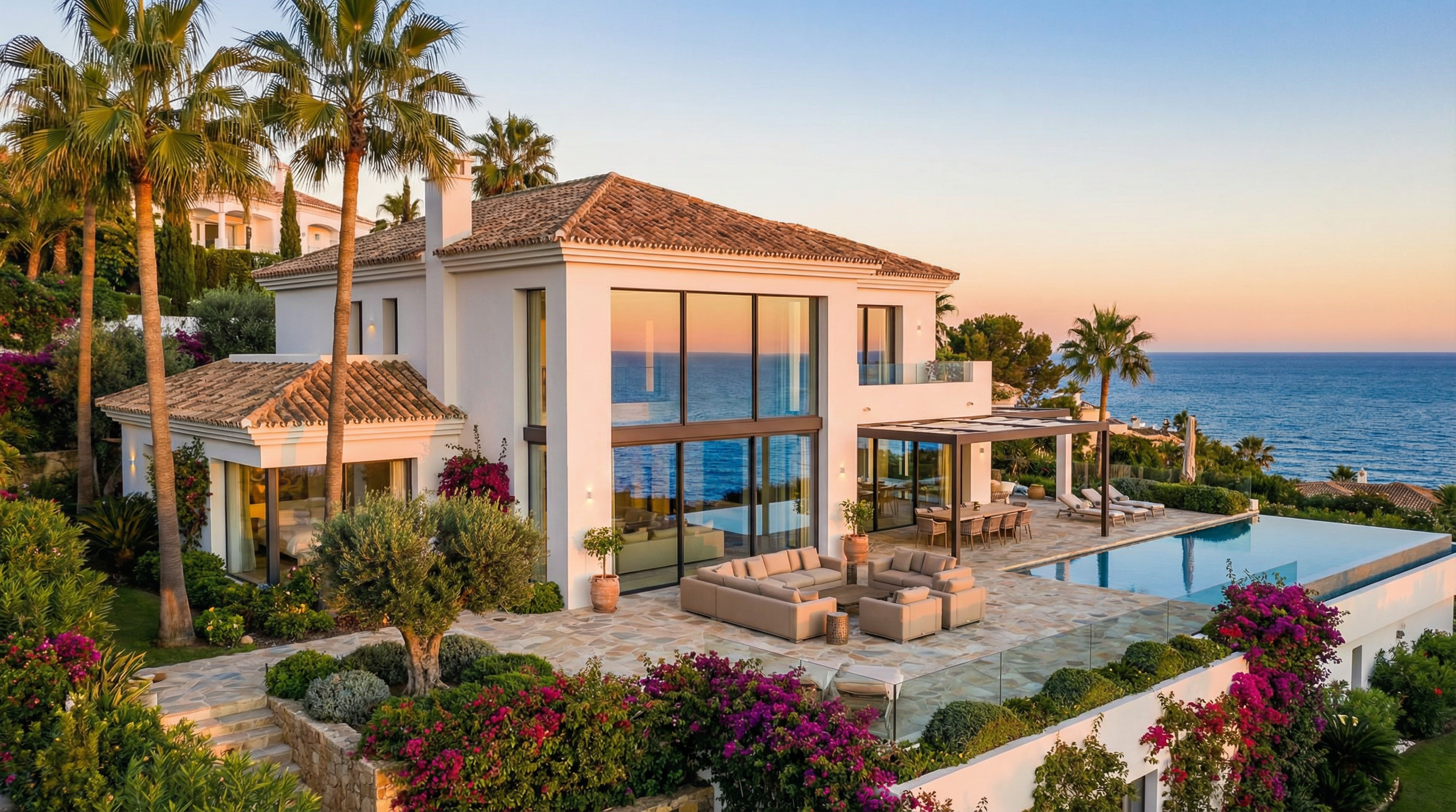 A stunning coastal villa in Costa del Sol, showcasing modern Mediterranean architecture with glass windows and lush gardens at sunset.